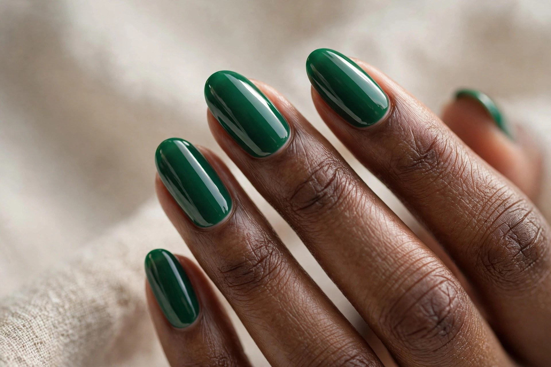 Dark-skinned woman's hand with emerald green glossy manicured nails