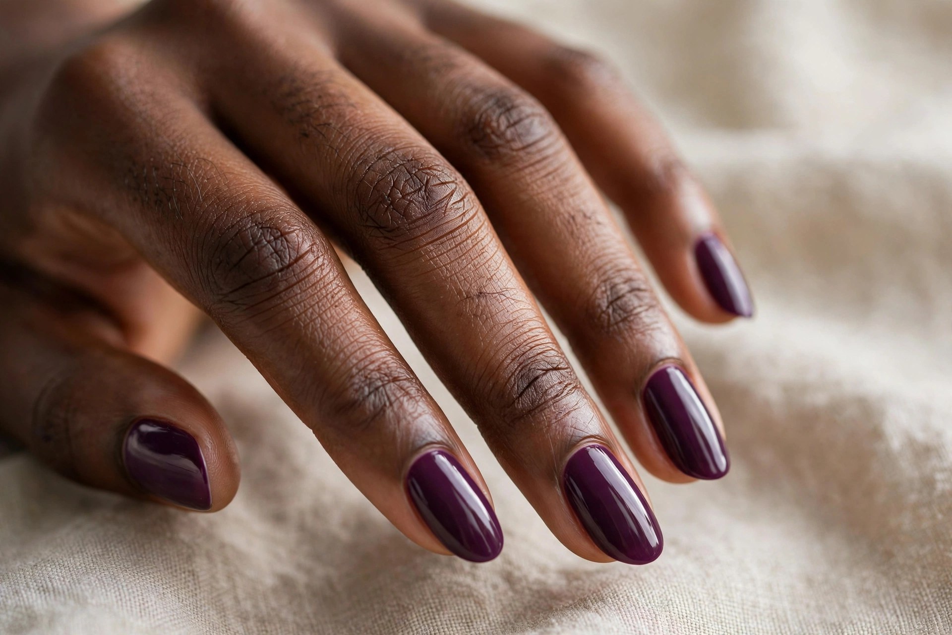 Dark-skinned woman's hand with deep plum purple manicured nails