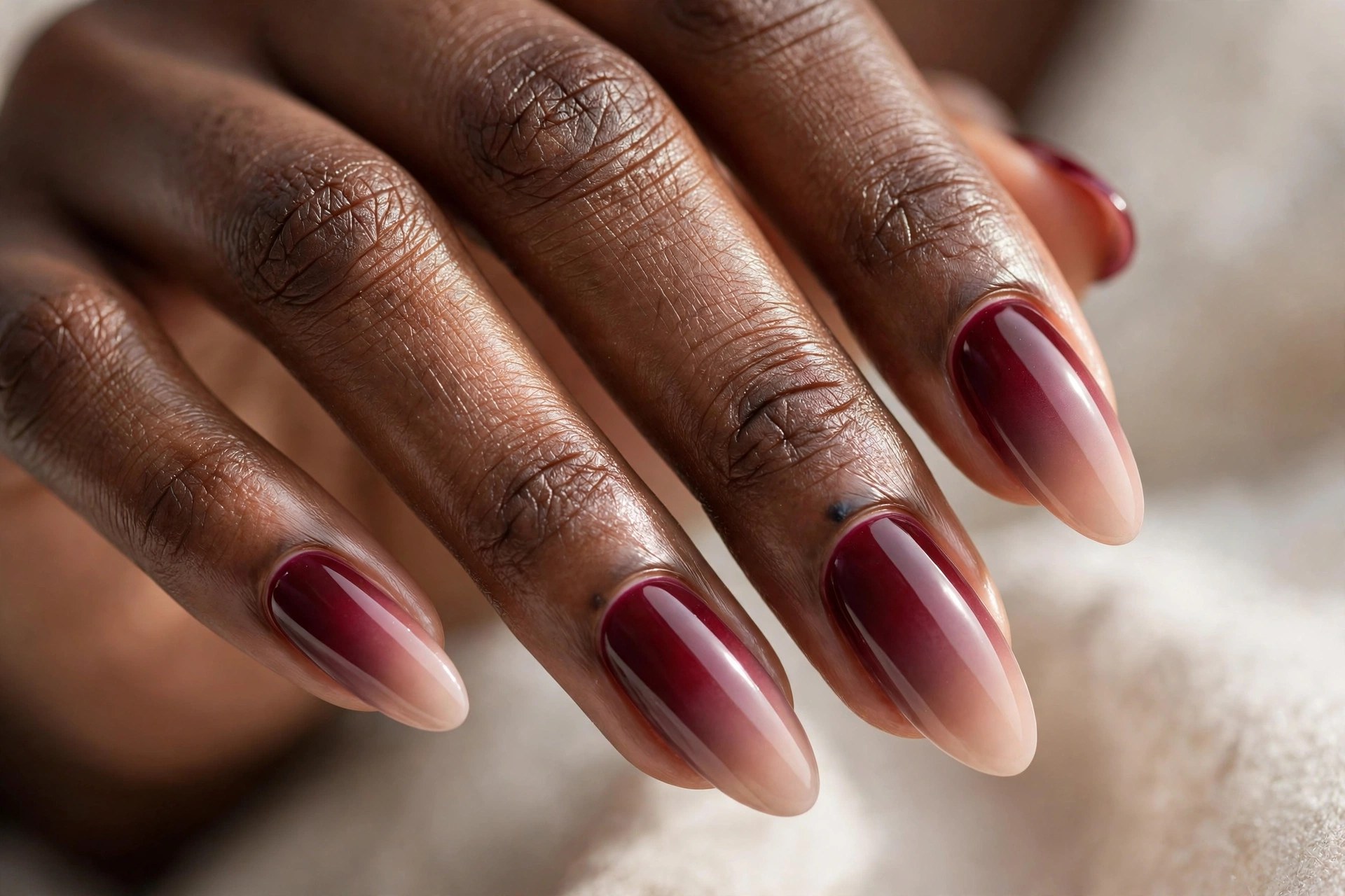 Dark-skinned woman's hand with wine to nude ombre manicured nails