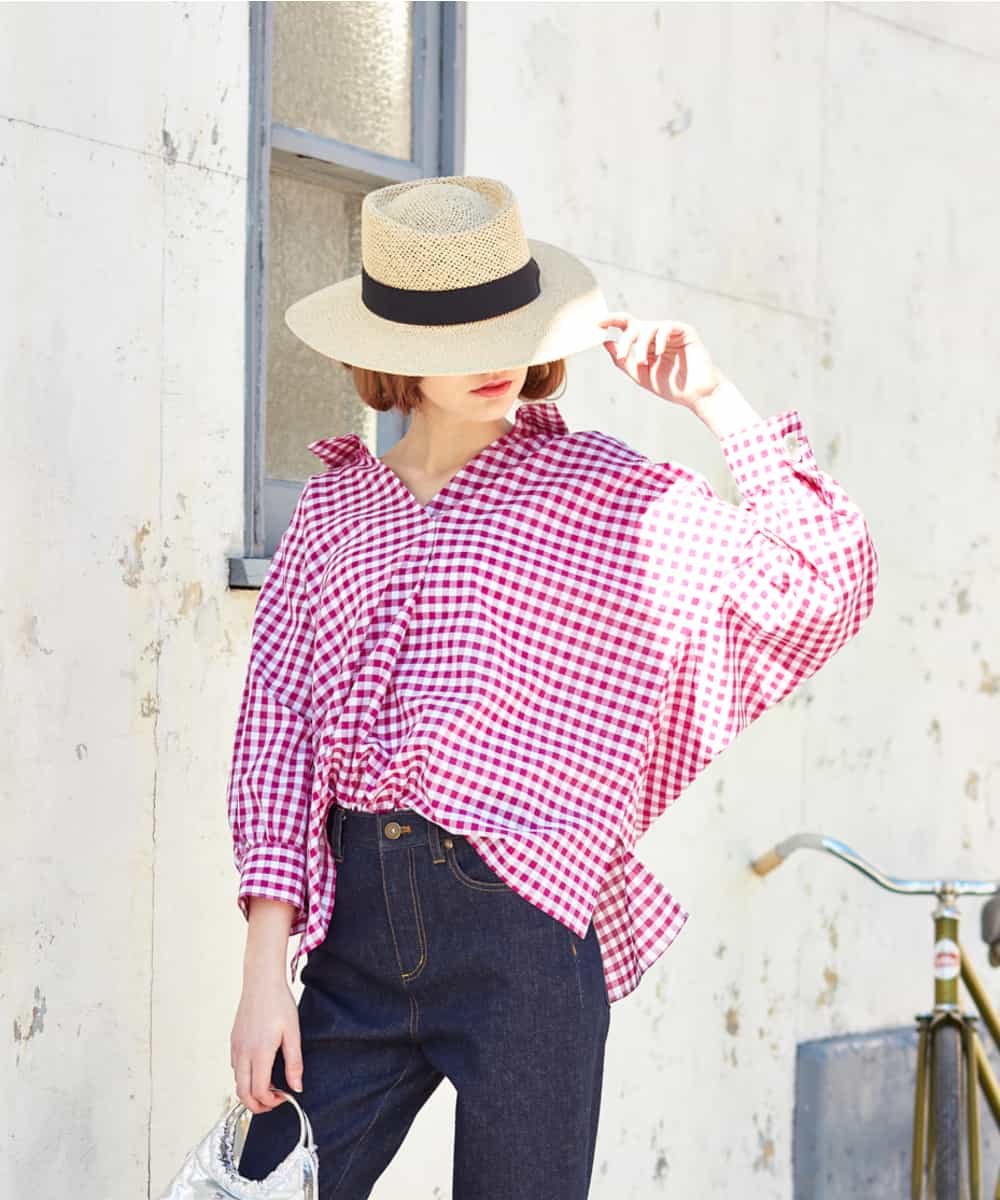Woman over 50 wearing gingham shirt, straight jeans and straw hat for apple picking