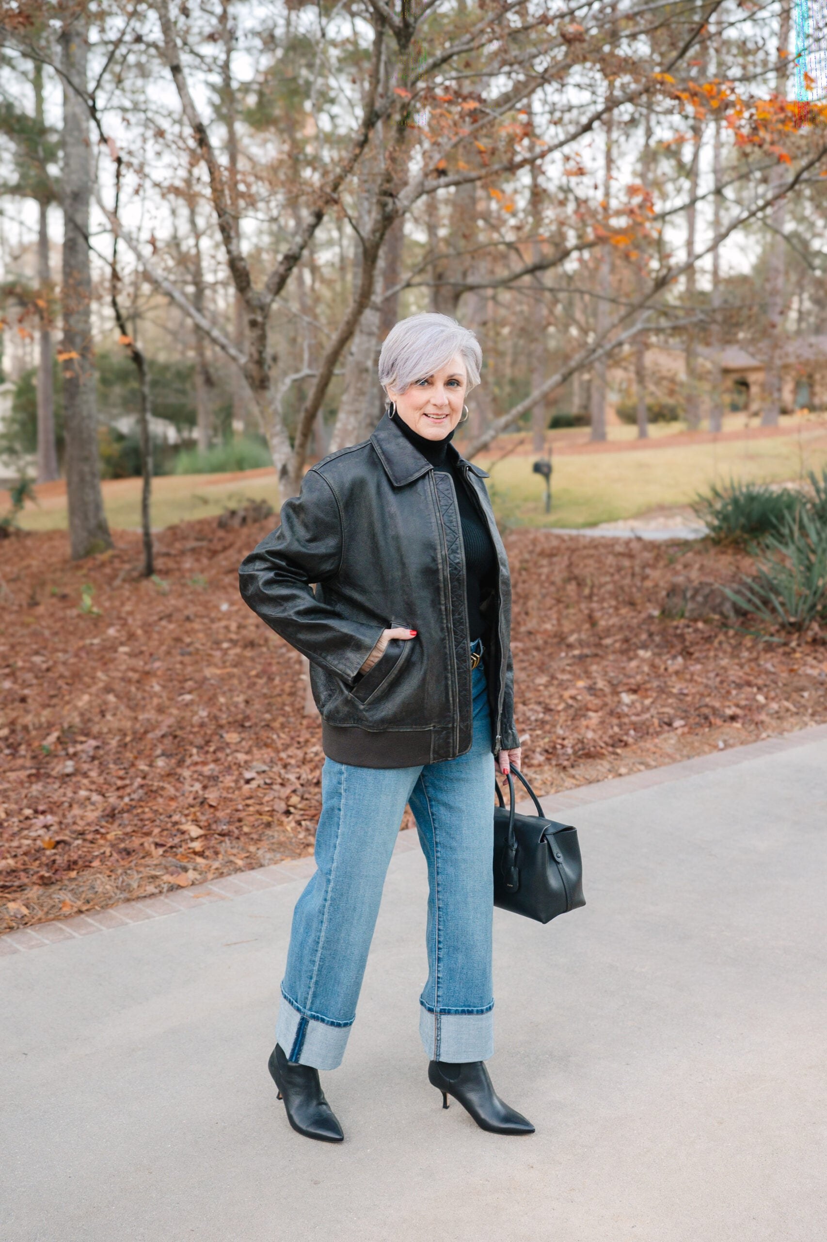 Woman over 50 wearing a black leather jacket with a black turtleneck and jeans