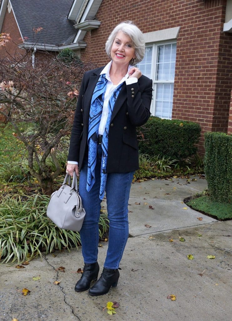 Black bomber jacket with white shirt and silk scarf on a woman over 50