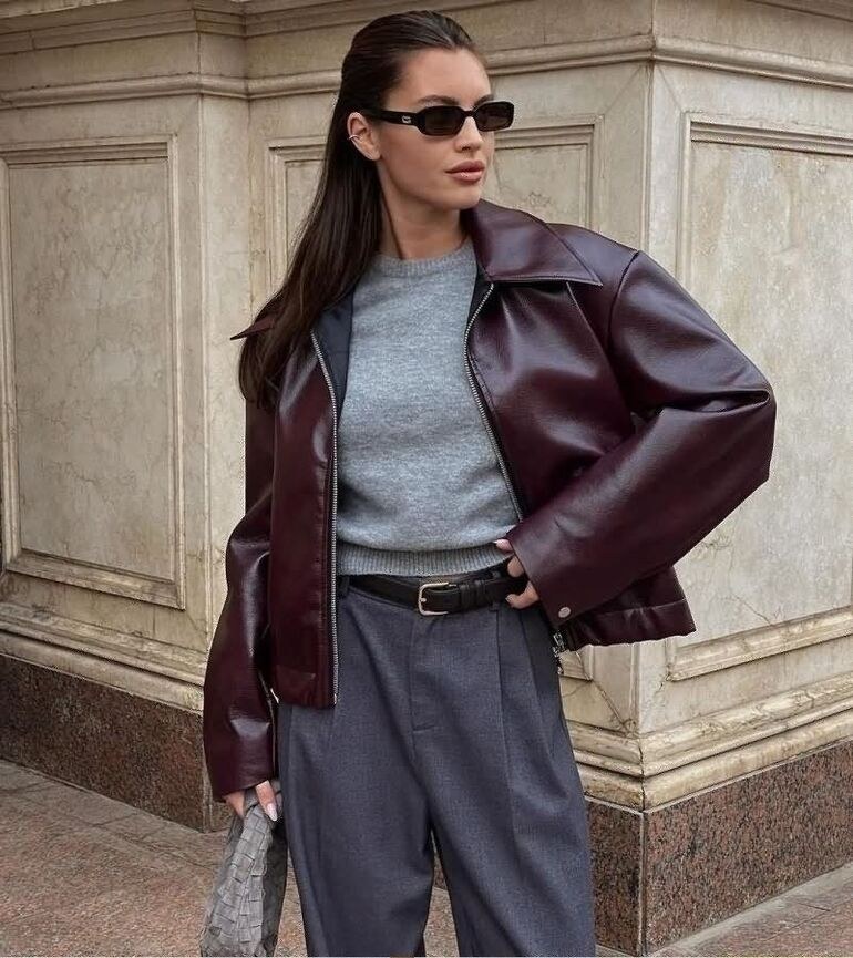 Woman wearing a burgundy leather jacket with a grey knit sweater and grey trousers