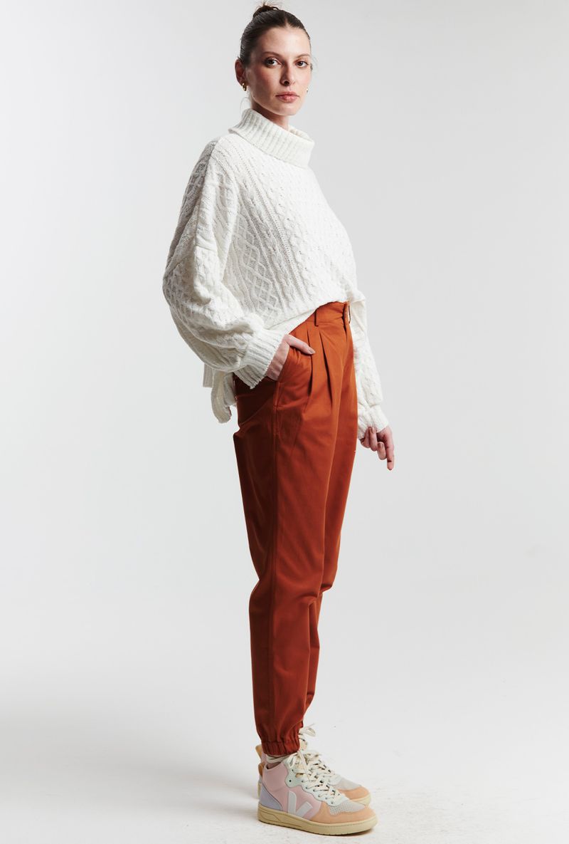 Cream cable knit sweater with rust corduroy trousers and sneakers