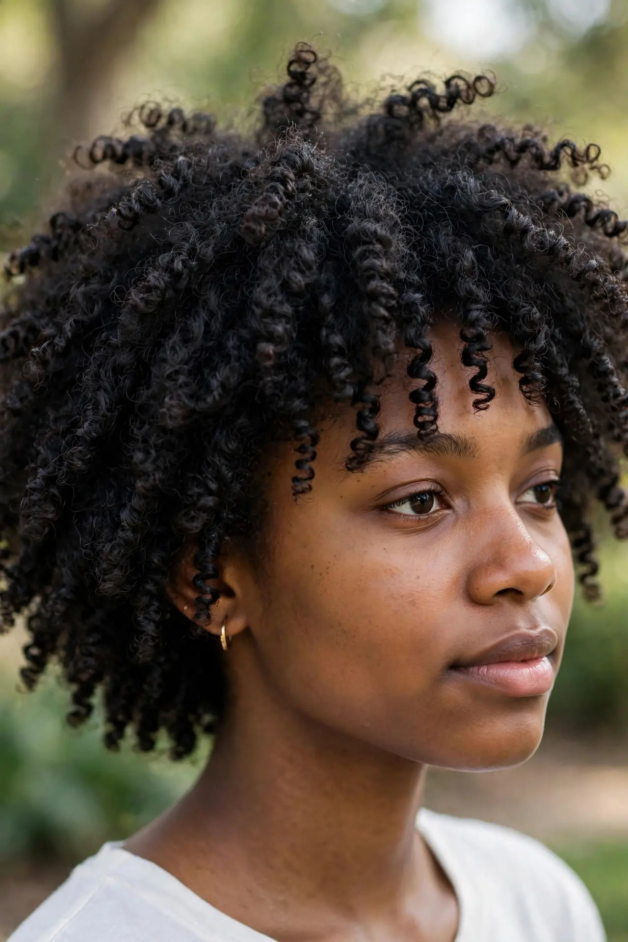 Young woman with tight springy coils with natural shrinkage, three-quarter view