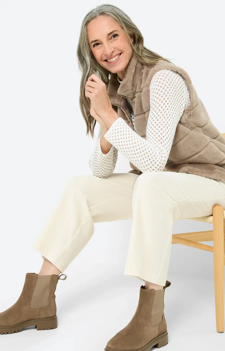 Woman over 50 in cream and soft neutral clothing with tan suede Chelsea boots