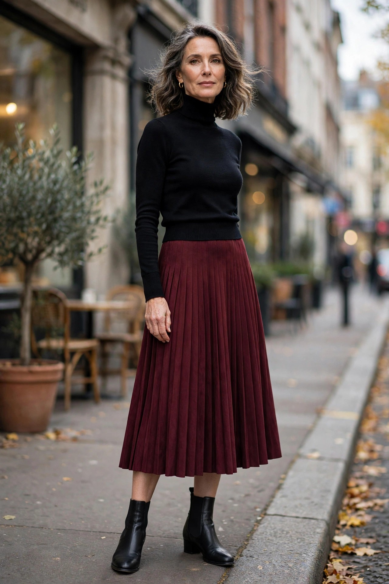 Woman in her 50s wearing black stretch-panel ankle booties with a burgundy midi skirt and black turtleneck