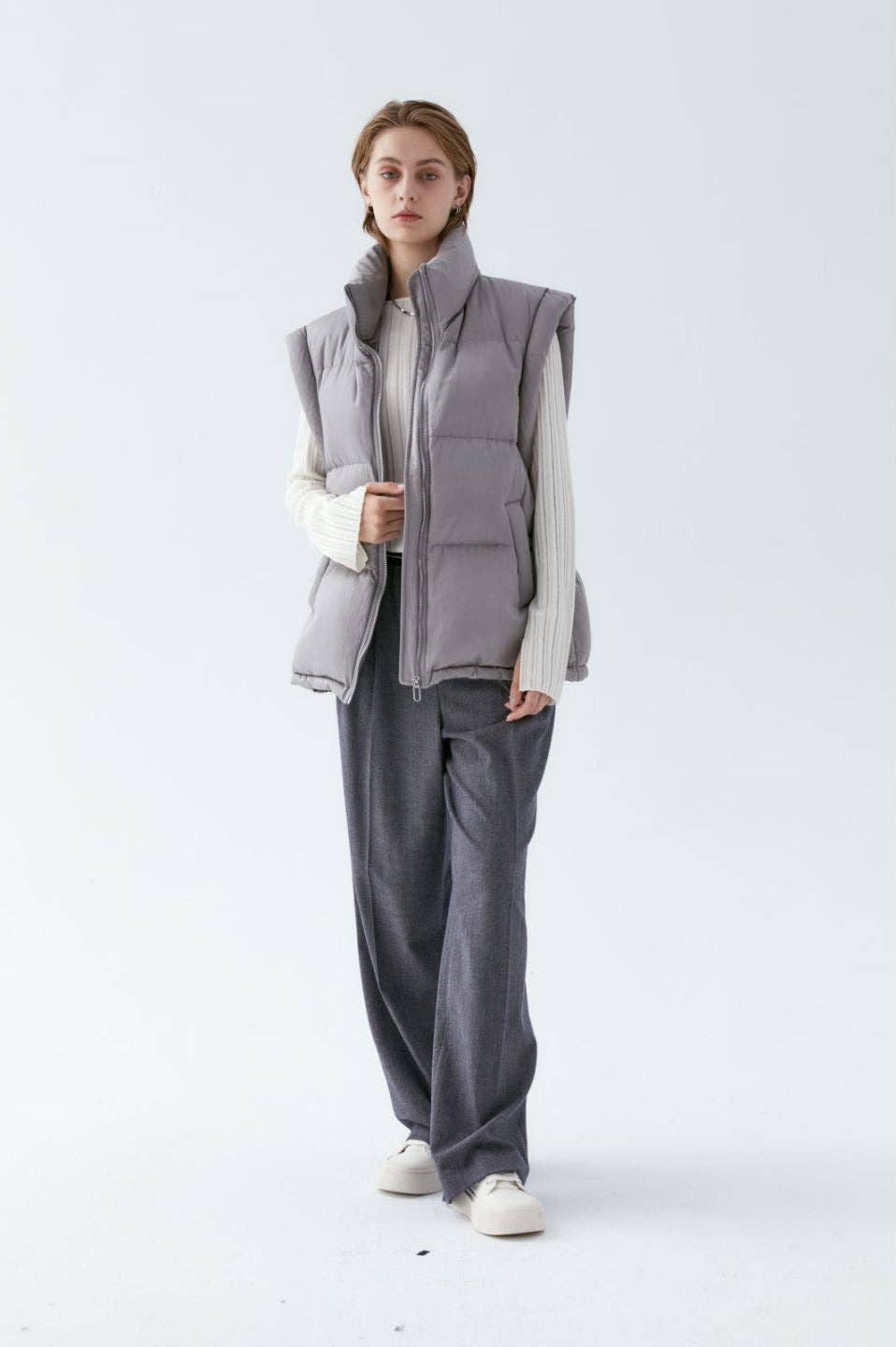 Cream puffer vest with grey knit sweater, grey trousers and white sneakers — fresh fall look