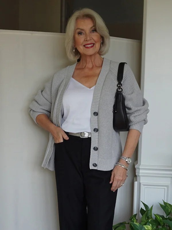 Woman over 50 in a belted chunky cream cardigan with wide trousers and boots