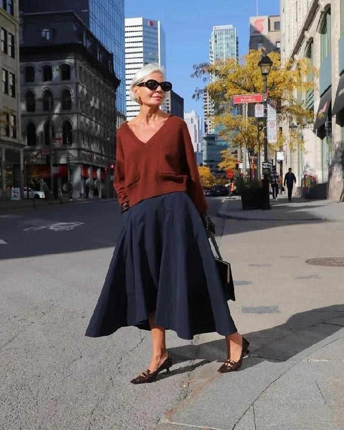 Woman over 50 wearing a cropped cardigan with a silk midi skirt and ballet flats