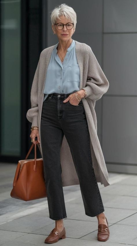 Woman over 50 wearing a grey v-neck cardigan with silk cami and dark jeans