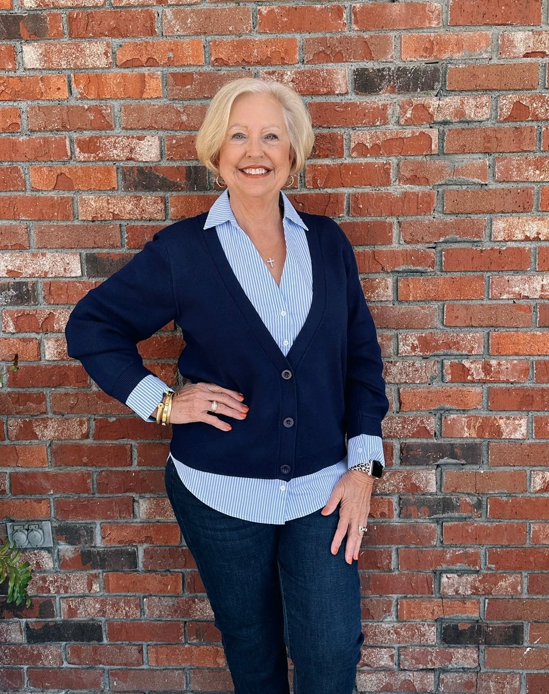 Woman over 50 in a striped cardigan with navy A-line skirt and loafers
