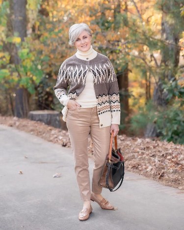 Woman over 50 wearing a cream turtleneck cardigan with chocolate wide trousers