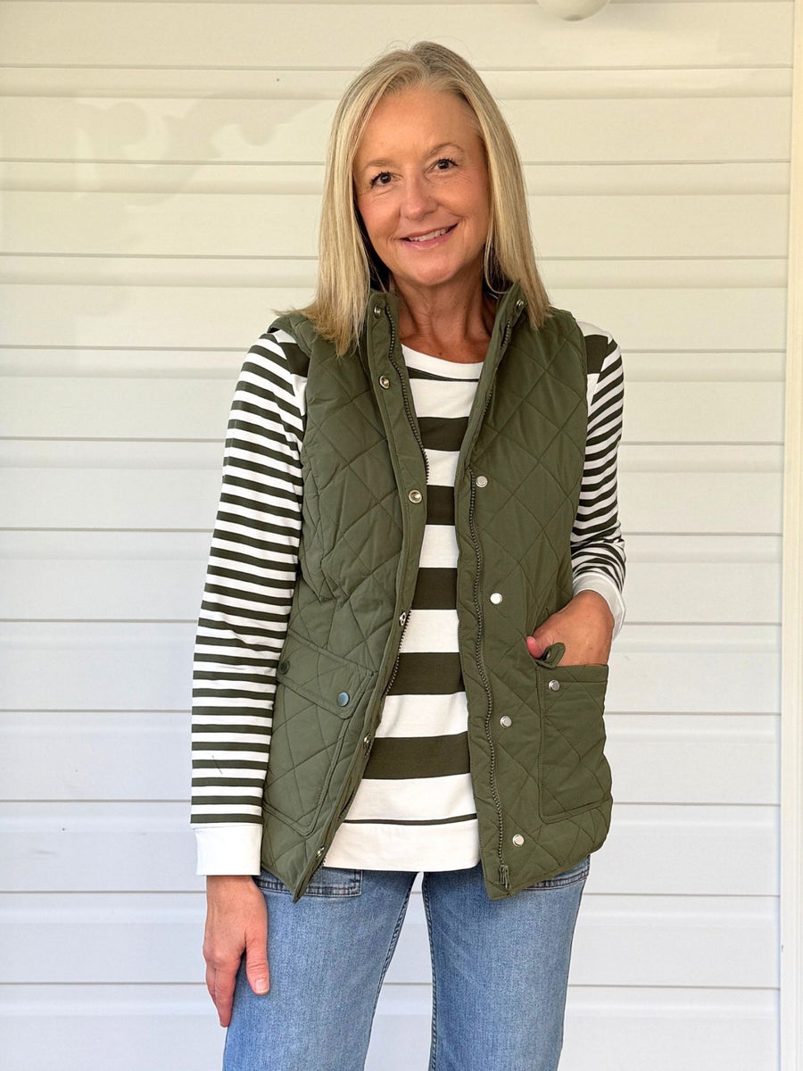 Woman over 50 in striped long sleeve tee quilted vest and jeans