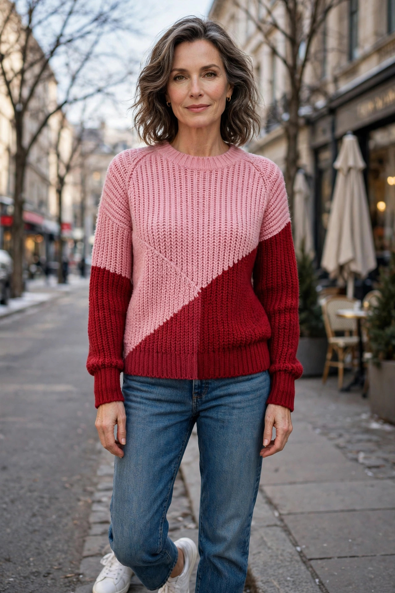 Woman over 50 in a pink-and-red colorblock sweater and jeans on a bright winter day