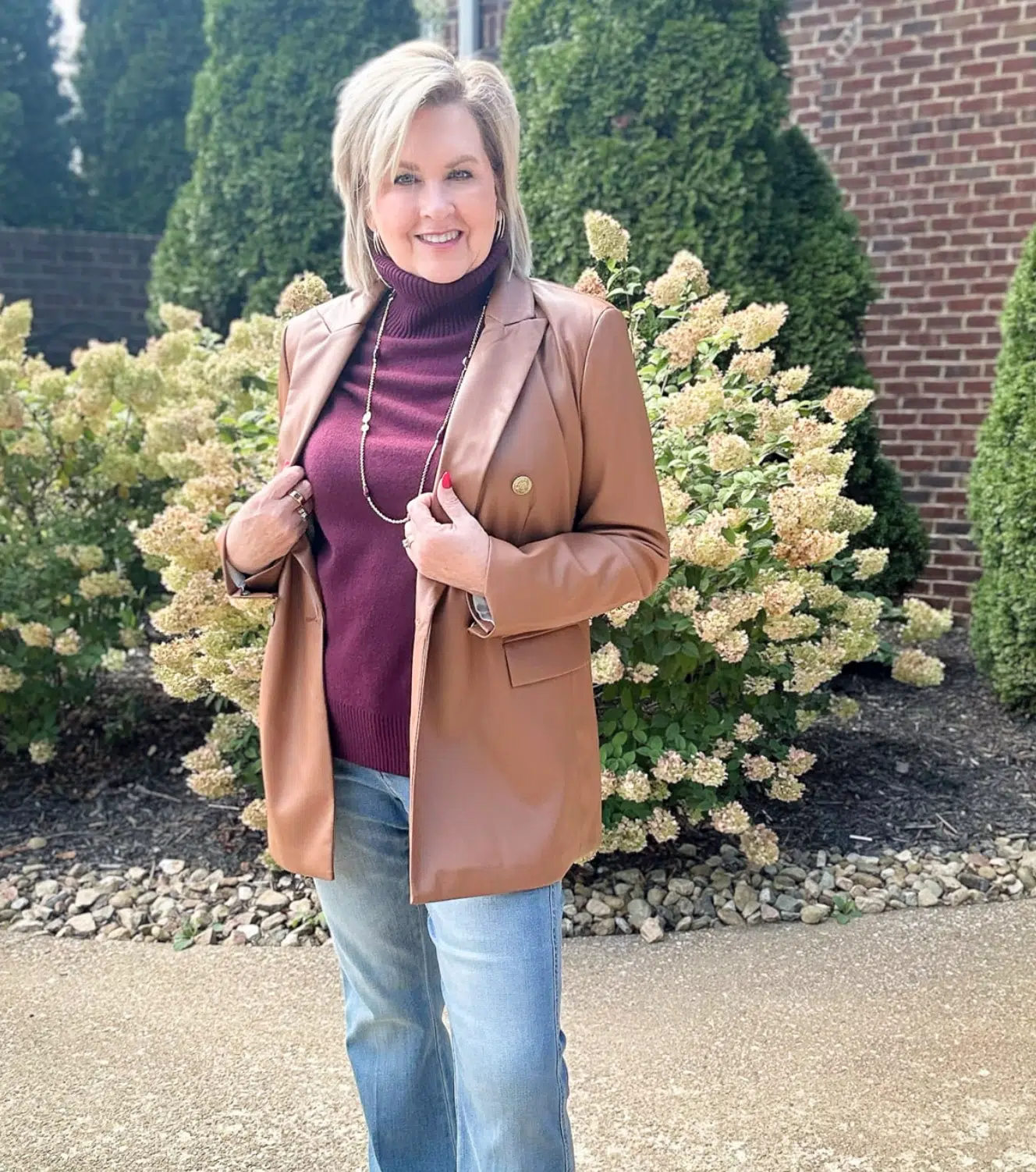 Woman over 50 wearing camel blazer with turtleneck and jeans