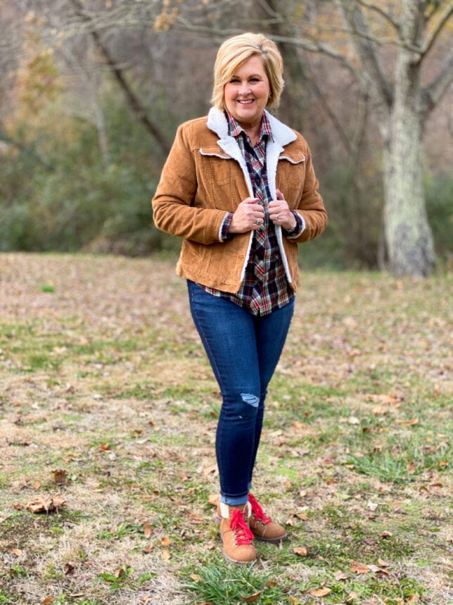 Woman over 50 wearing a tan suede sherpa jacket, plaid shirt and jeans for fall