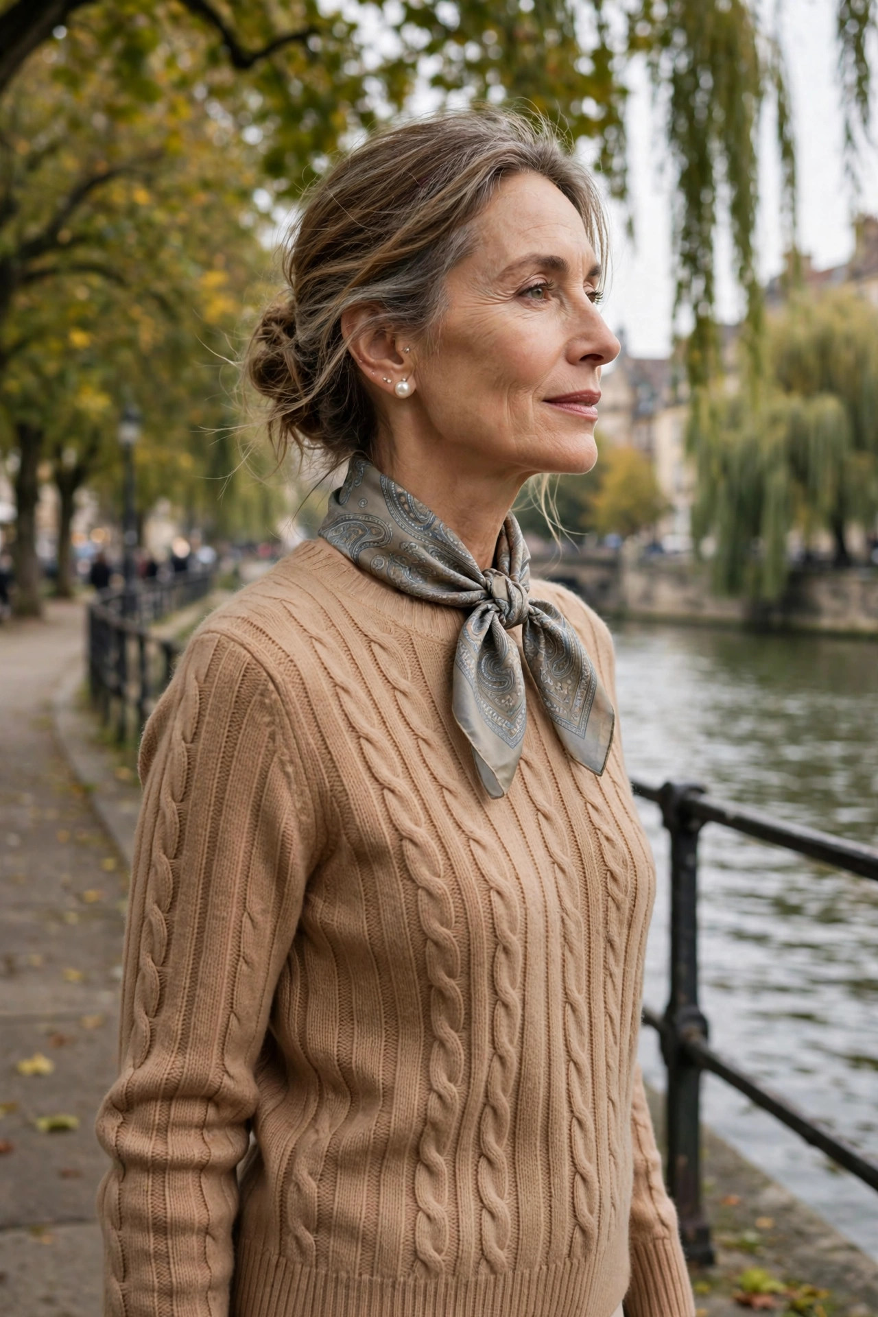 Woman over 50 in a camel sweater with a paisley silk scarf tied at the neck