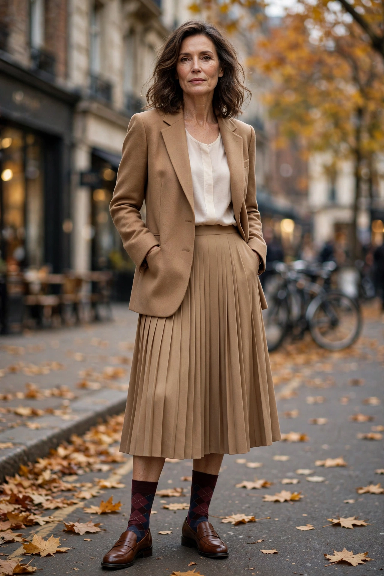 Woman over 50 in burgundy argyle crew socks, brown loafers, camel pleated skirt, blazer