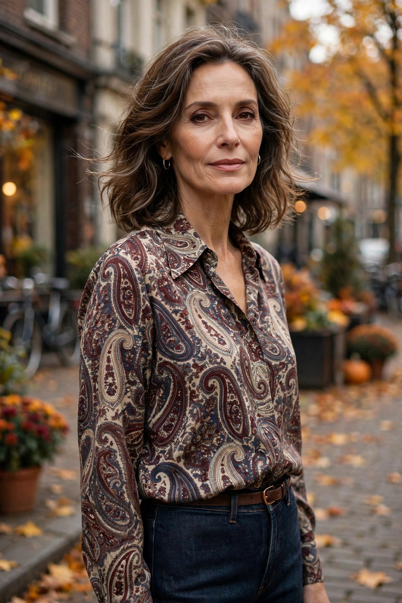 Woman in her 50s wearing a vintage paisley print blouse with dark straight-leg jeans