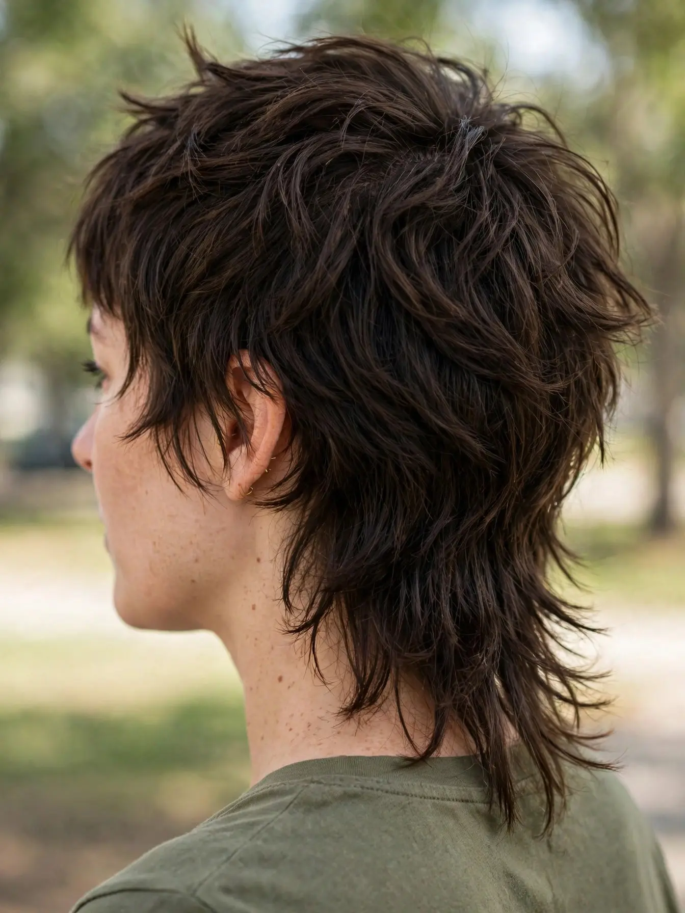 Woman with a mullet-inspired shag haircut, short choppy layers on top and a longer shaggy back