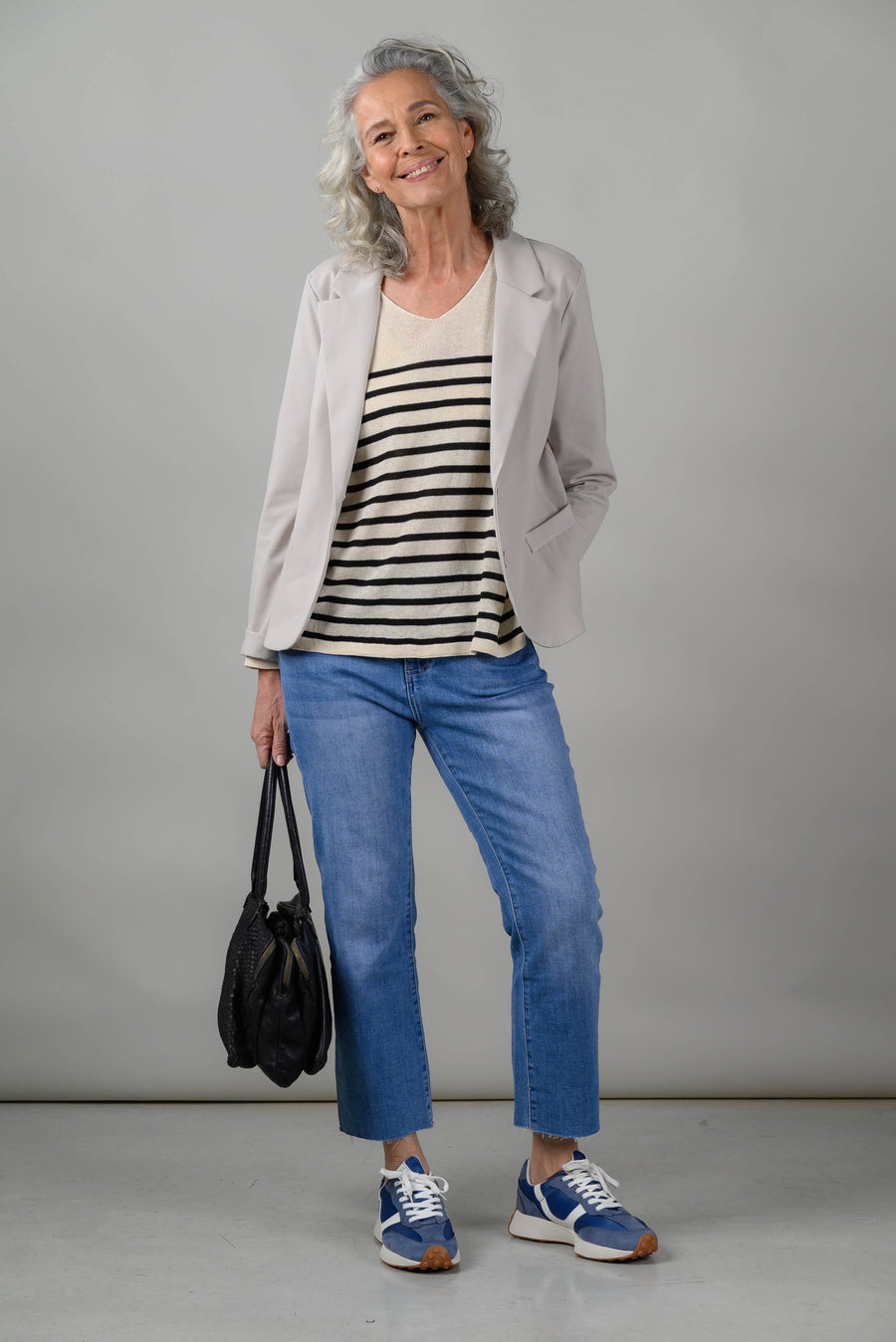 Woman over 60 wearing knit top straight jeans and open blazer