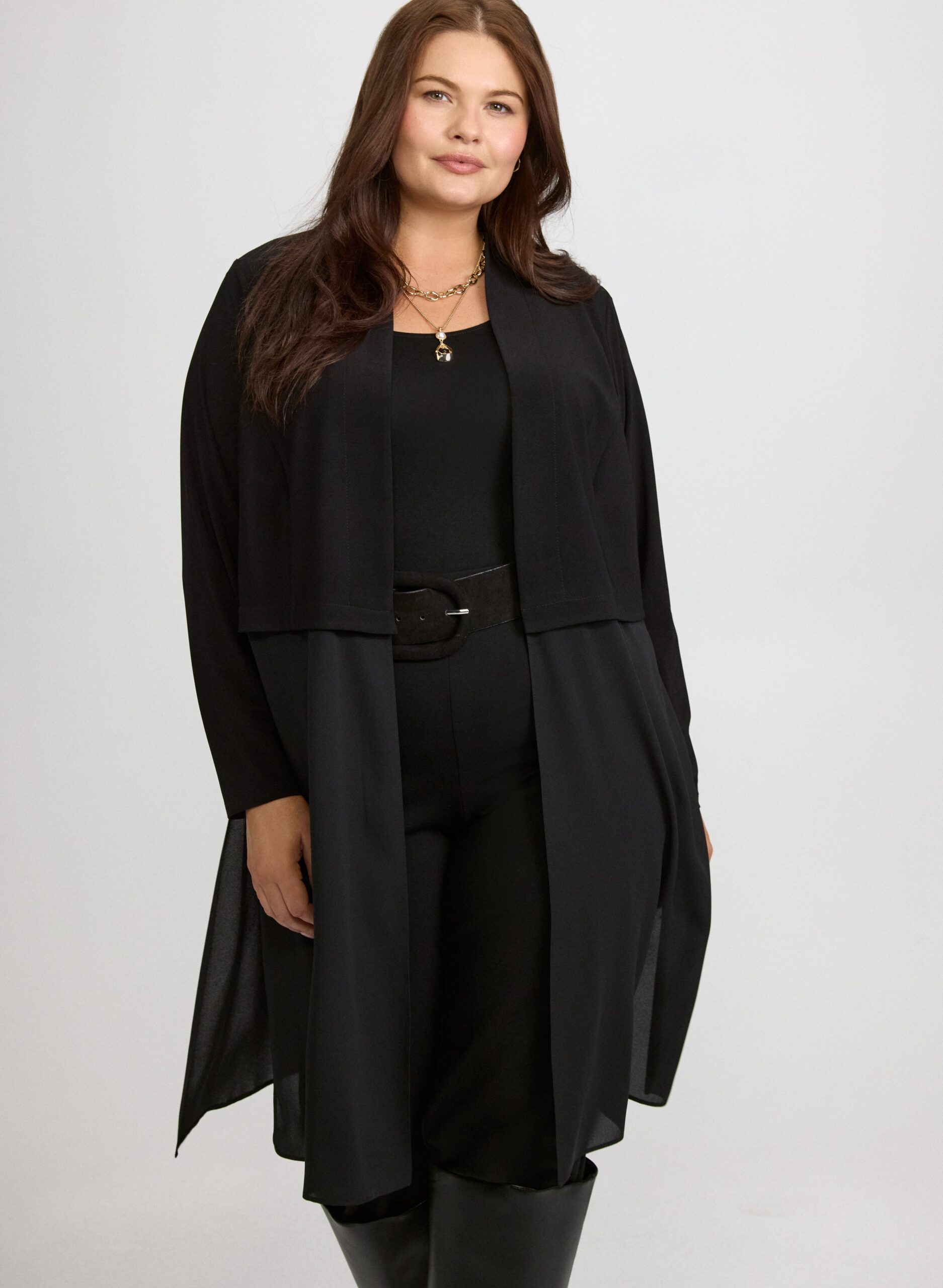 Plus size woman over 60 wearing long cardigan belted over black outfit