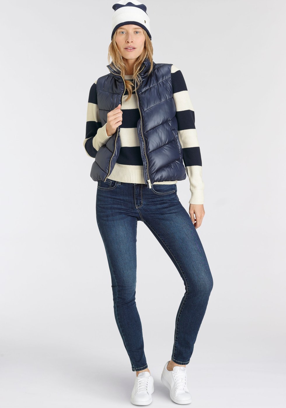 Mustard beanie with navy puffer vest and striped tee on a woman over 50