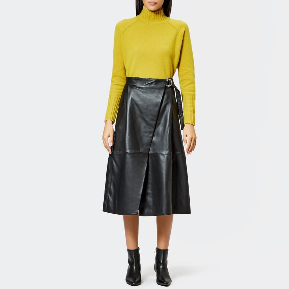 Mustard midi skirt with a black turtleneck and black boots on a woman over 50