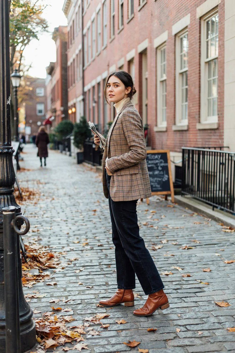 Woman over 50 wearing a mustard plaid blazer with cream knit and dark jeans