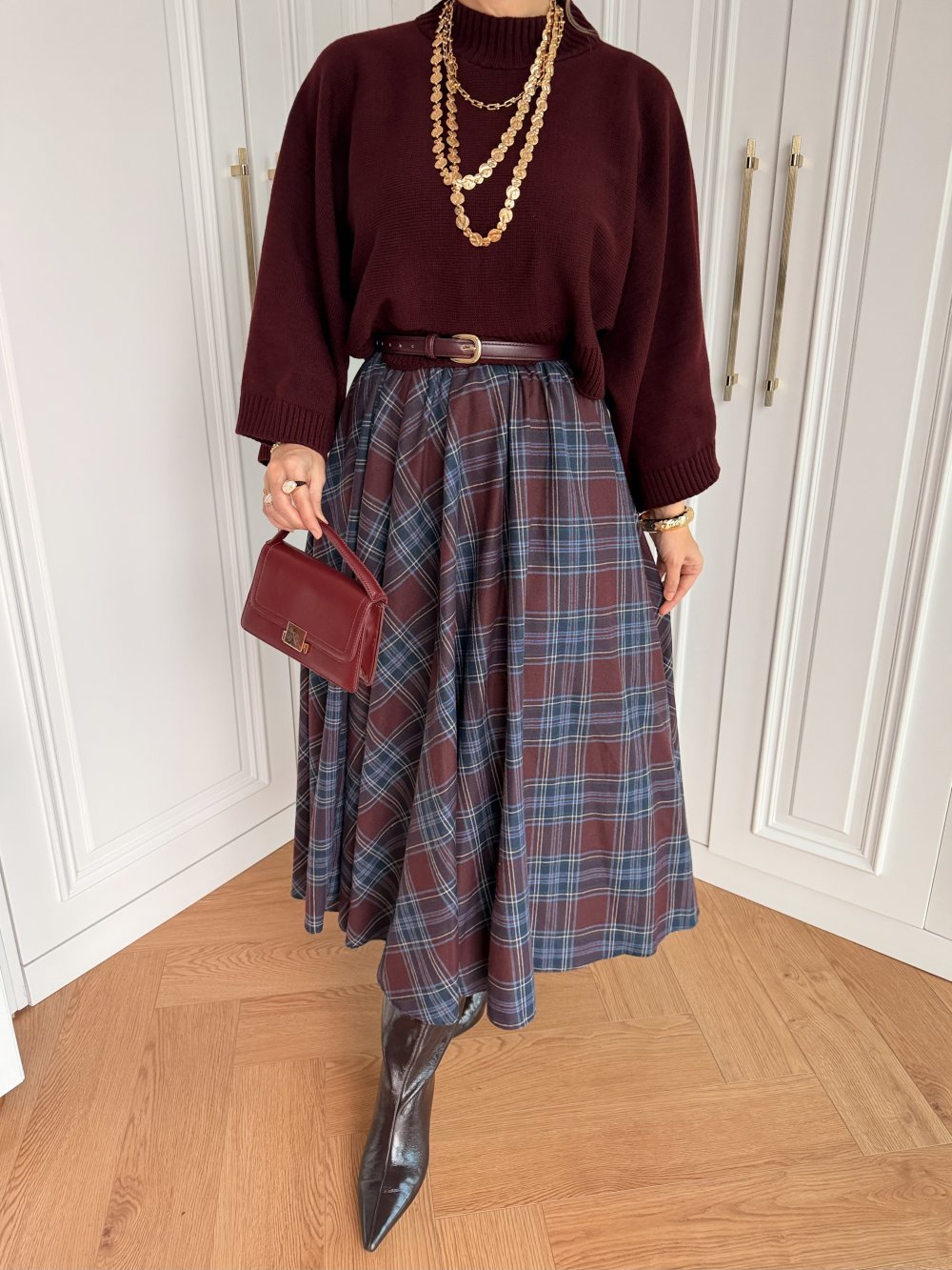 Mustard turtleneck with a burgundy skirt and gold jewelry on a woman over 50
