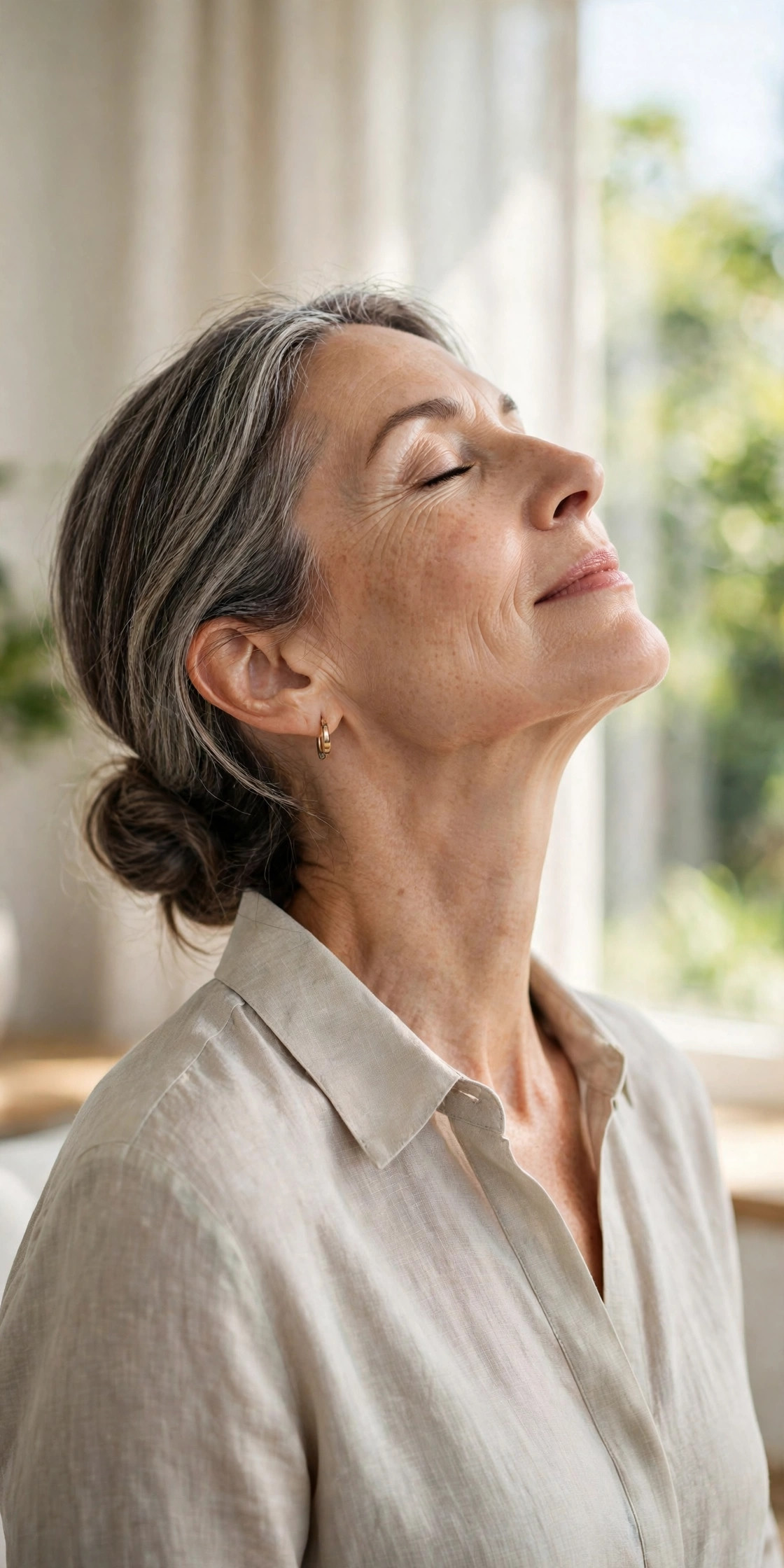 A woman in her 50s doing a gentle chin-lift neck stretch exercise