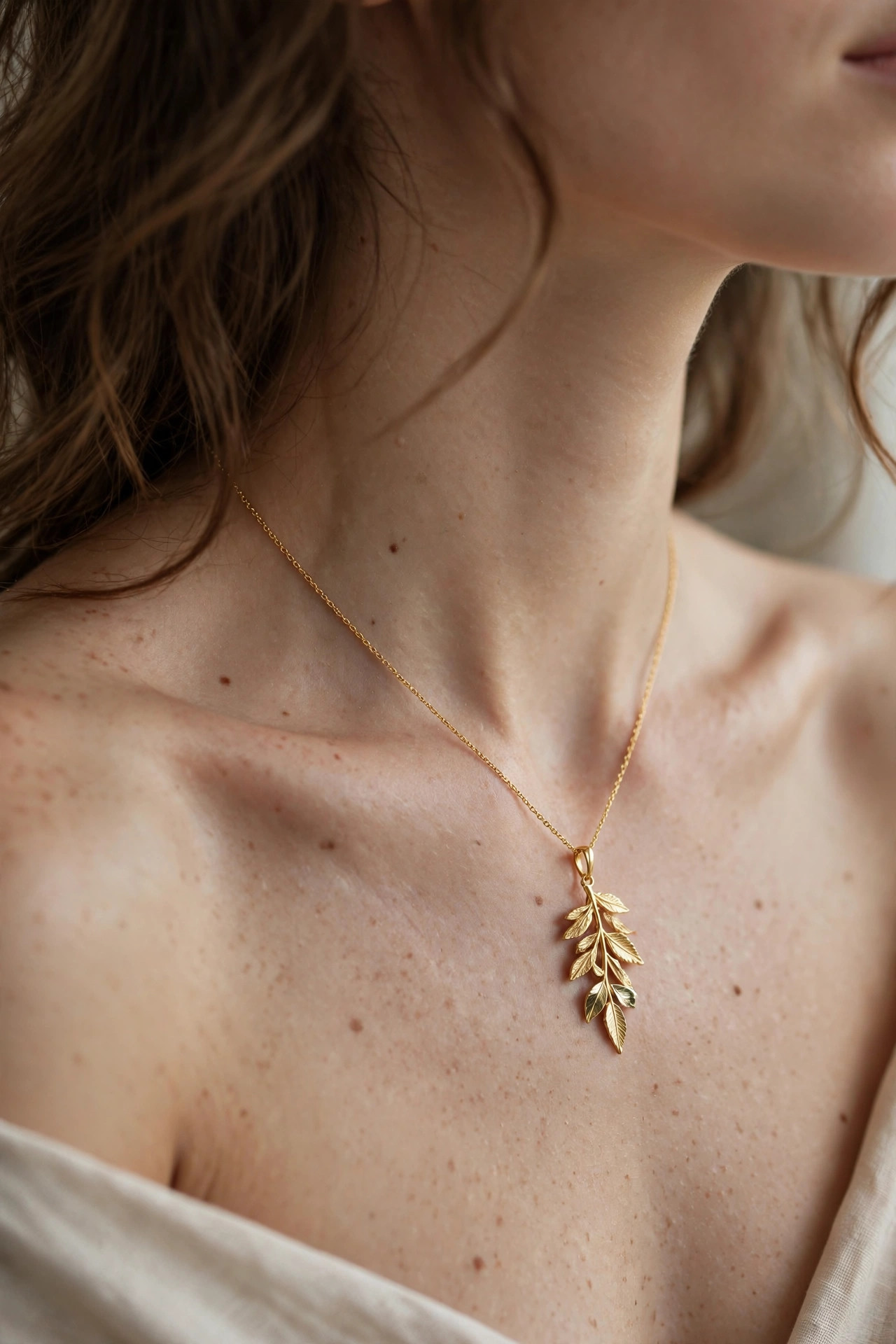 Close-up of an elegant gold pendant necklace on a woman's neck