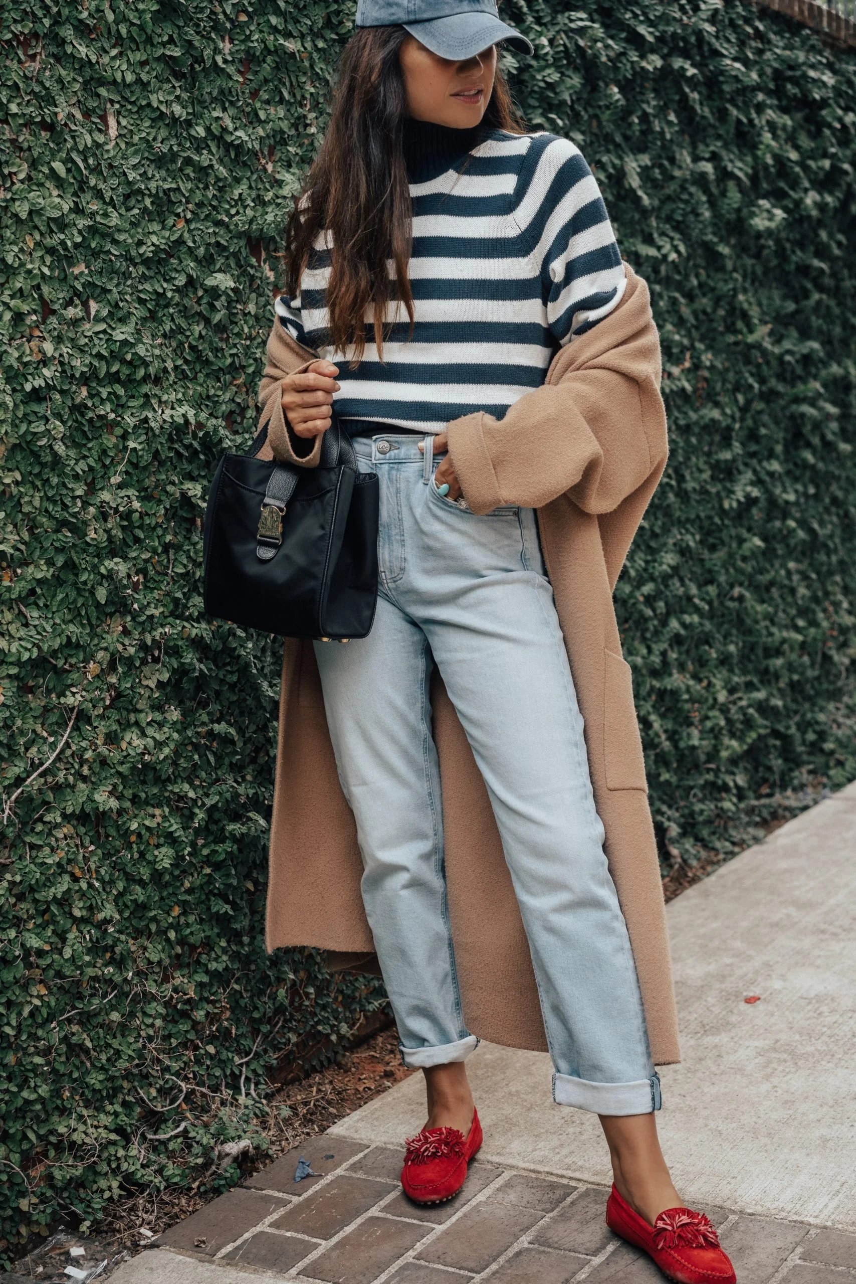 Navy wool coat with striped knit sweater, cream jeans and white sneakers — casual November outfit