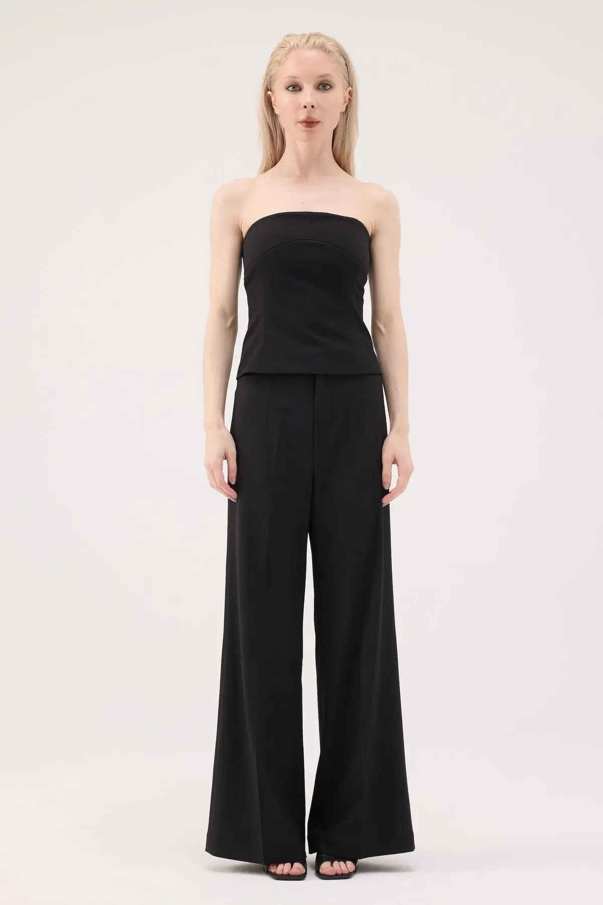 Woman wearing a black bandeau top with black wide-leg trousers