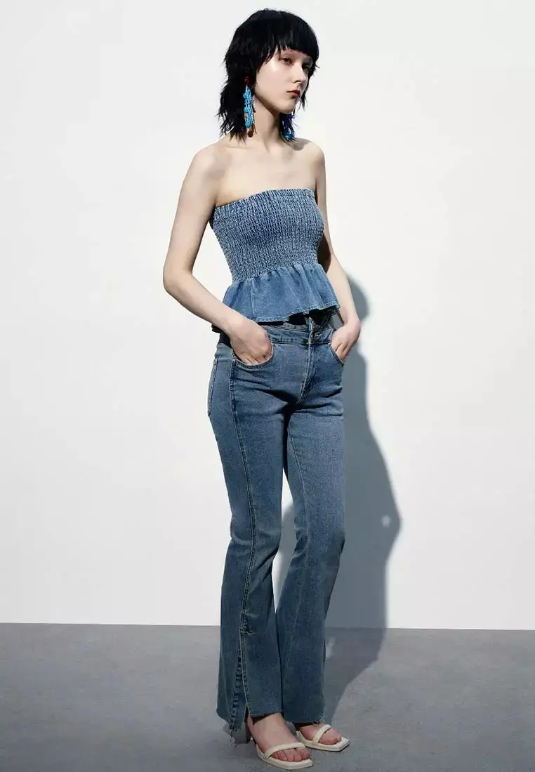 Woman wearing a strapless shirred denim peplum top with dark slim jeans