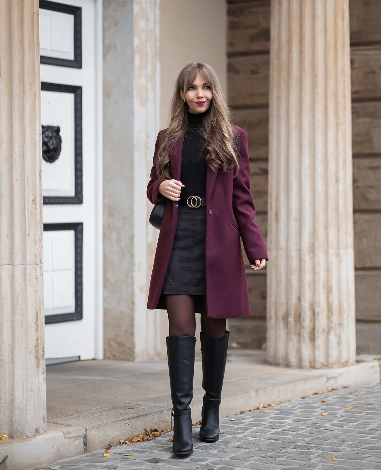 October outfit idea 25: black midi dress burgundy coat tall boots evening on a woman over 50