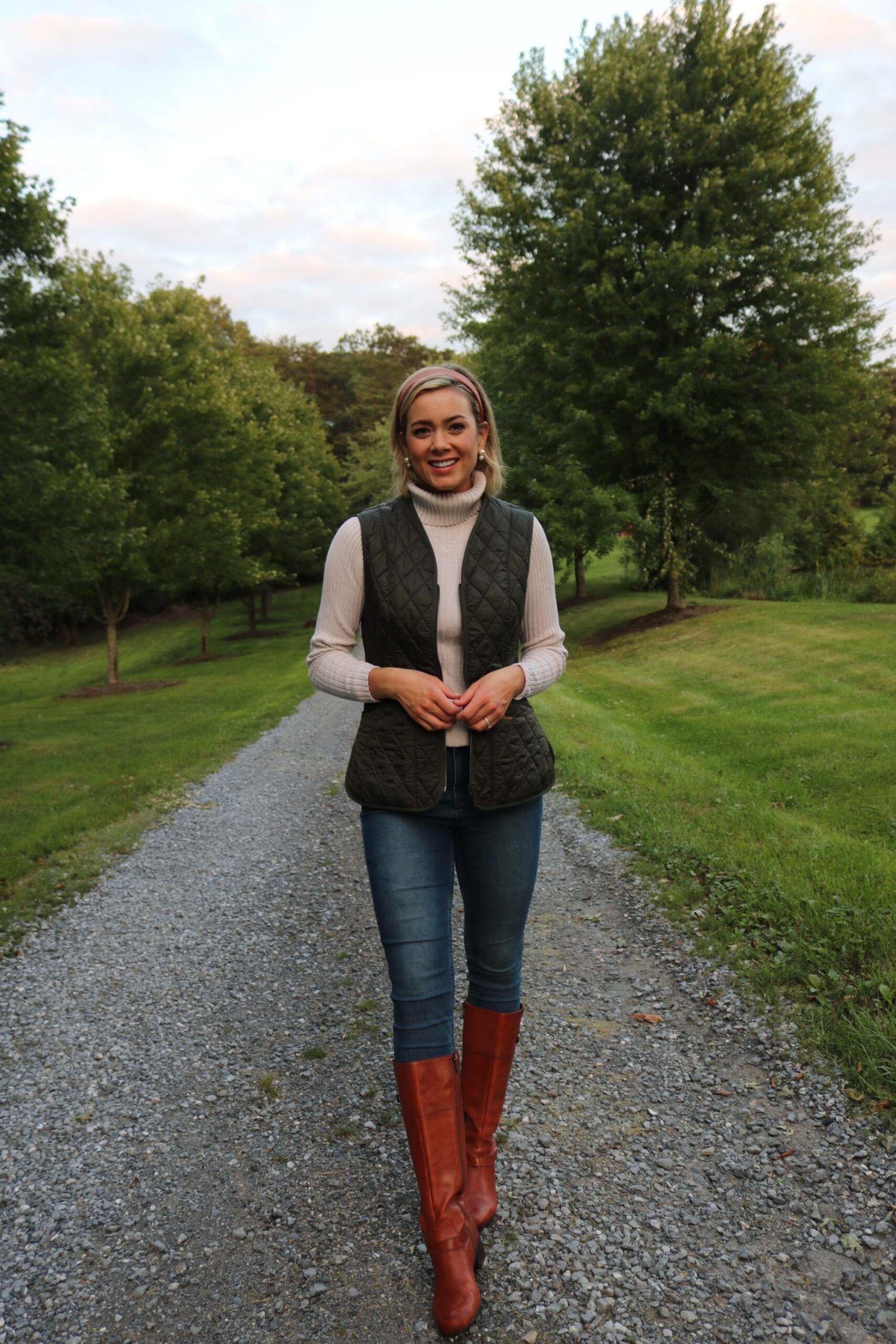 Woman over 50 wearing olive quilted jacket, cream cable knit sweater and wellies