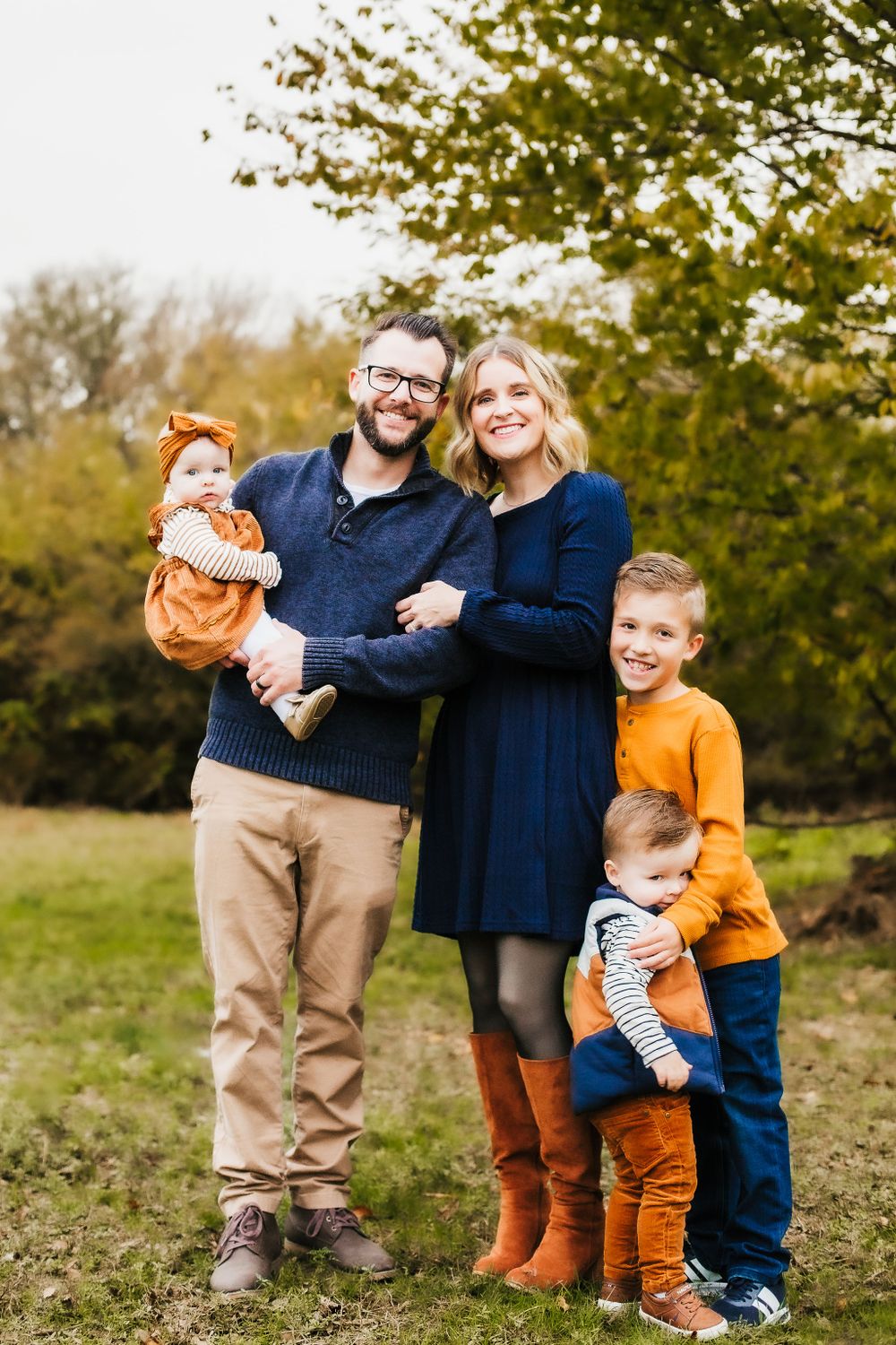 Coordinated family photo outfits in navy, cream and rust for fall pumpkin patch