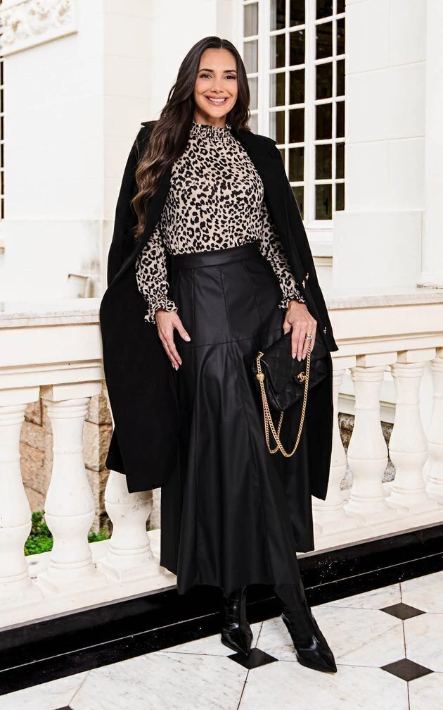 Woman over 50 wearing quilted jacket with leopard skirt and ankle boots