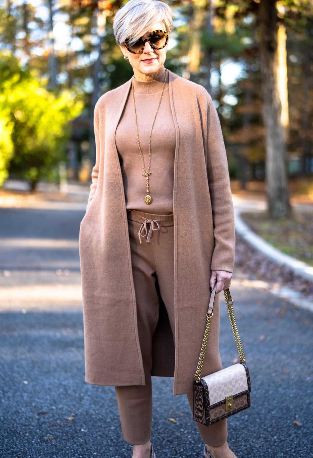 Rust cable knit sweater with light jeans and white sneakers