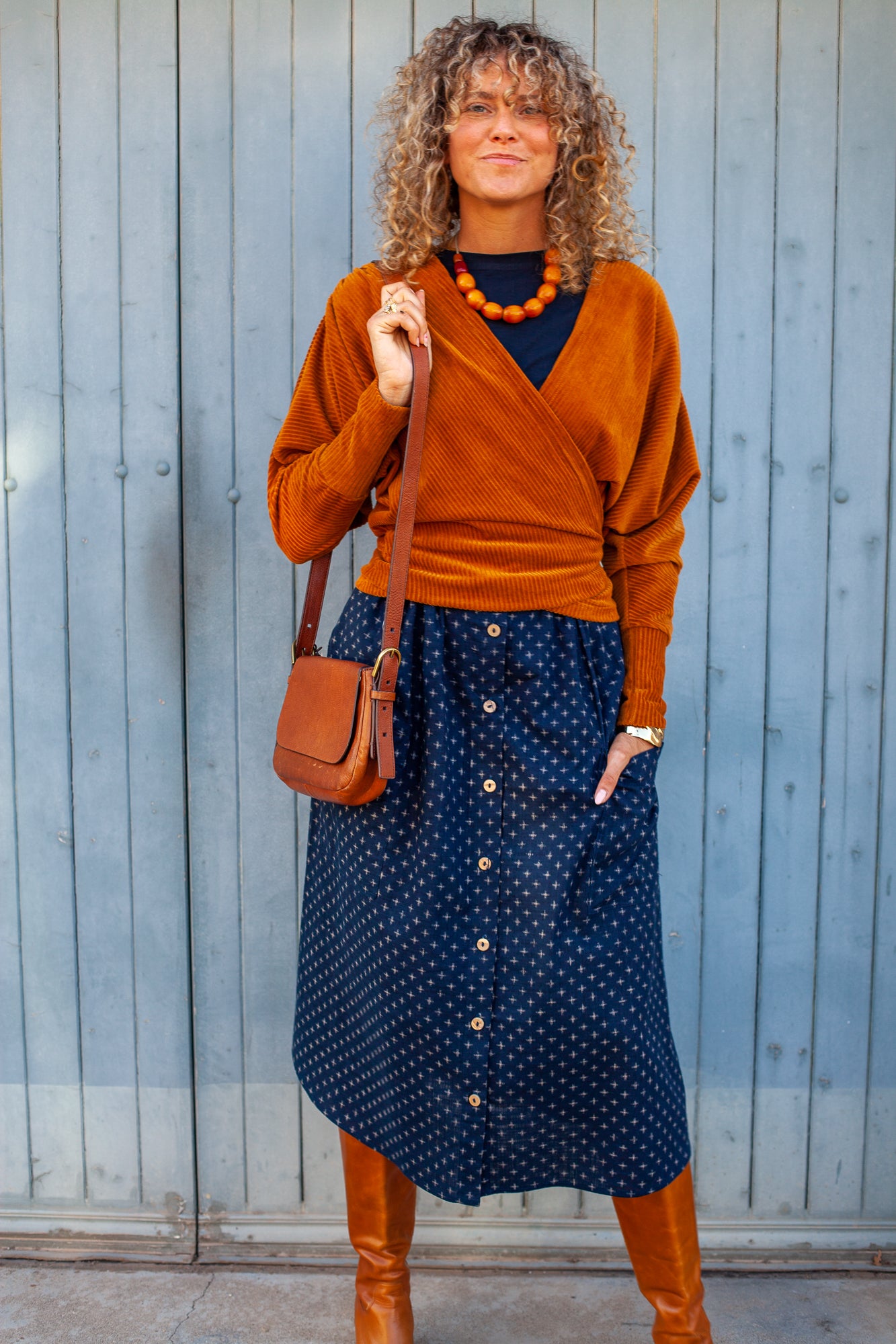 Rust midi dress with navy cardigan and knee-high boots