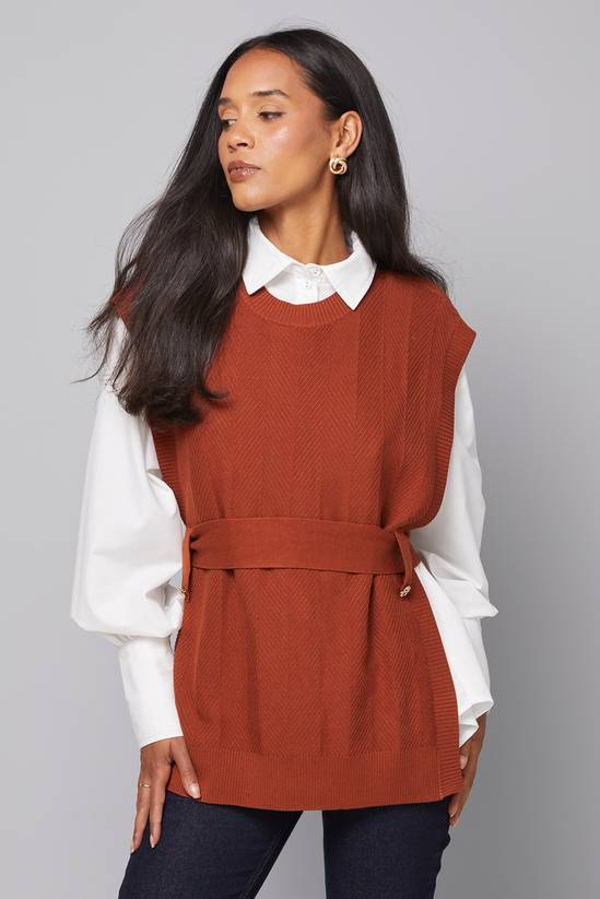 Rust V-neck sweater vest with a cream long-sleeve tee and jeans — easy fall outfit