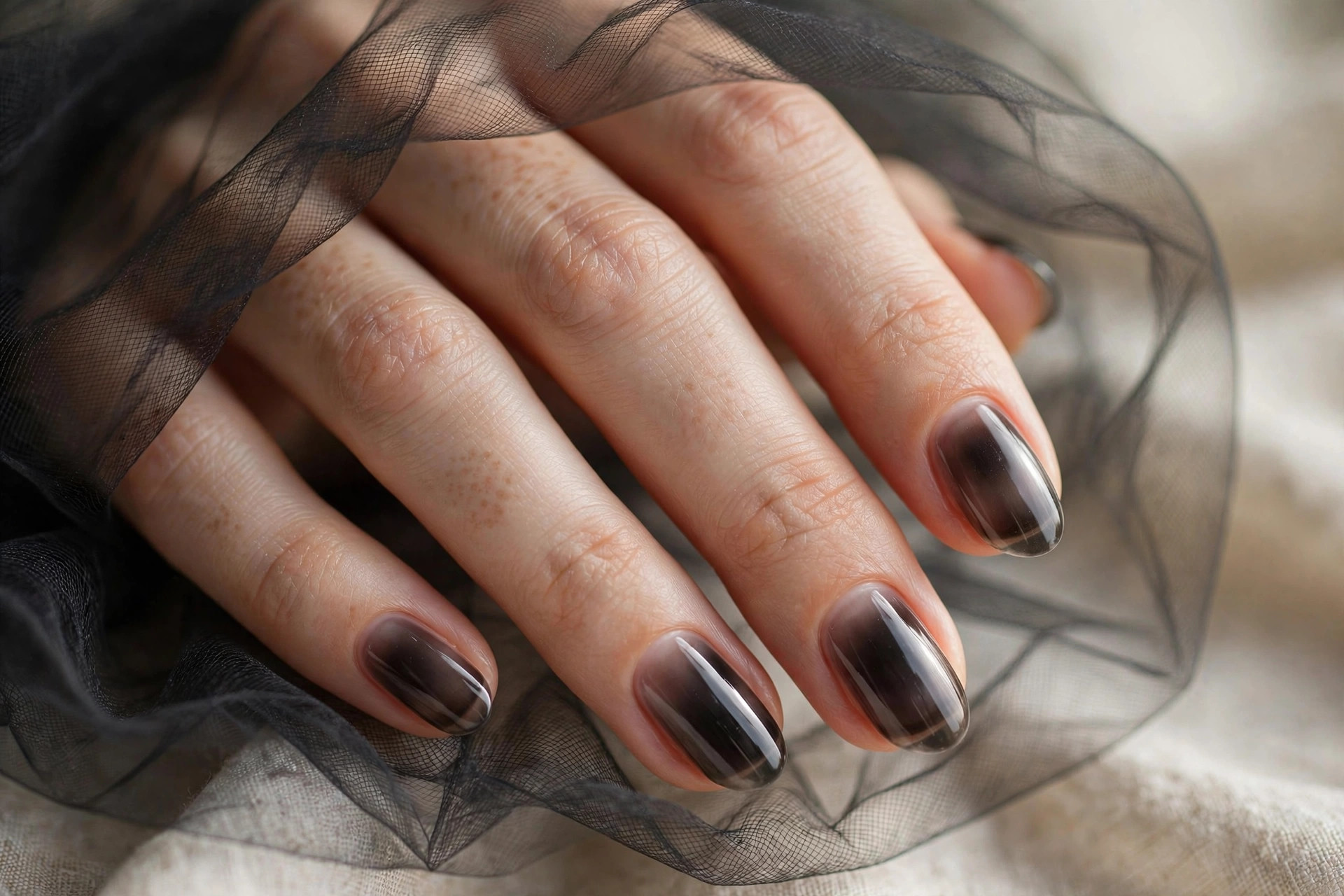 Short almond nails with one thin coat of translucent smoky black polish