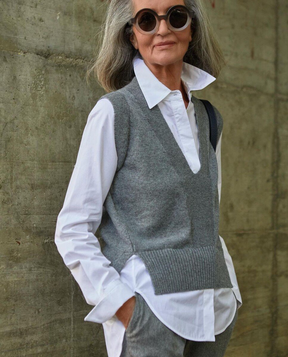 Grey sweater vest layered over grey turtleneck with grey trousers tonal outfit