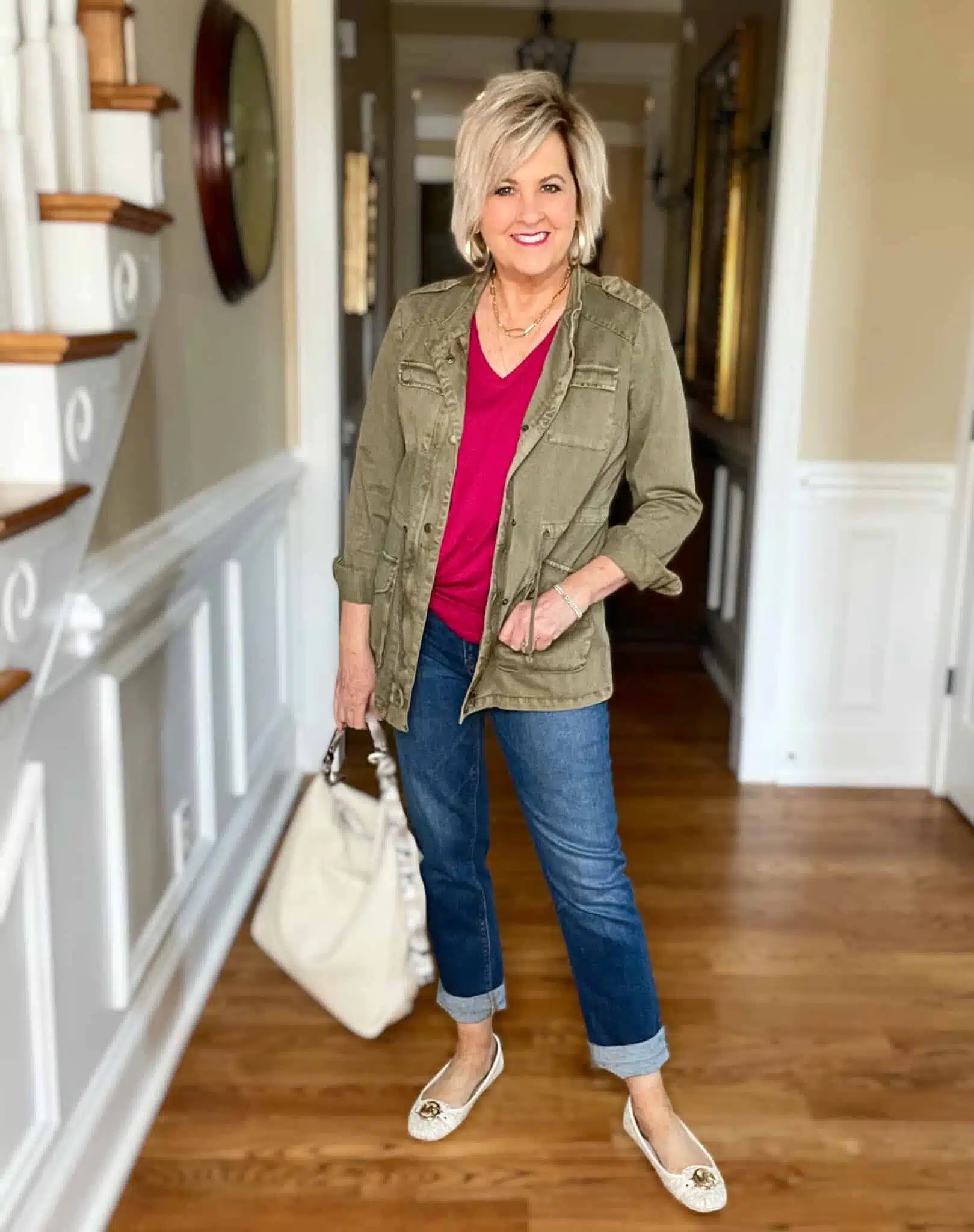 Olive utility jacket with pink sweater and cream jeans, woman over 50