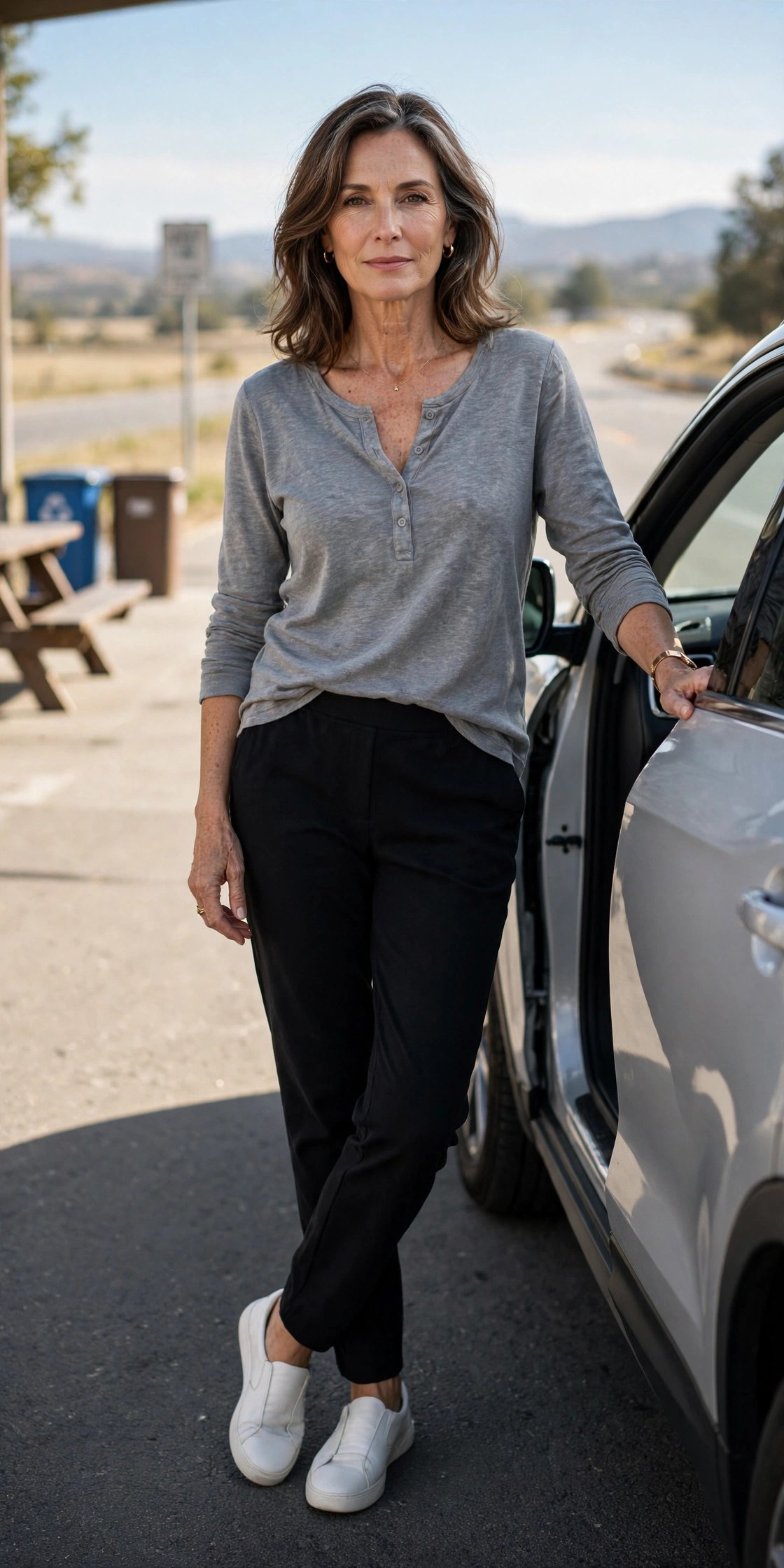 Woman in her 50s in black ponte-knit pants and grey henley at a highway rest stop