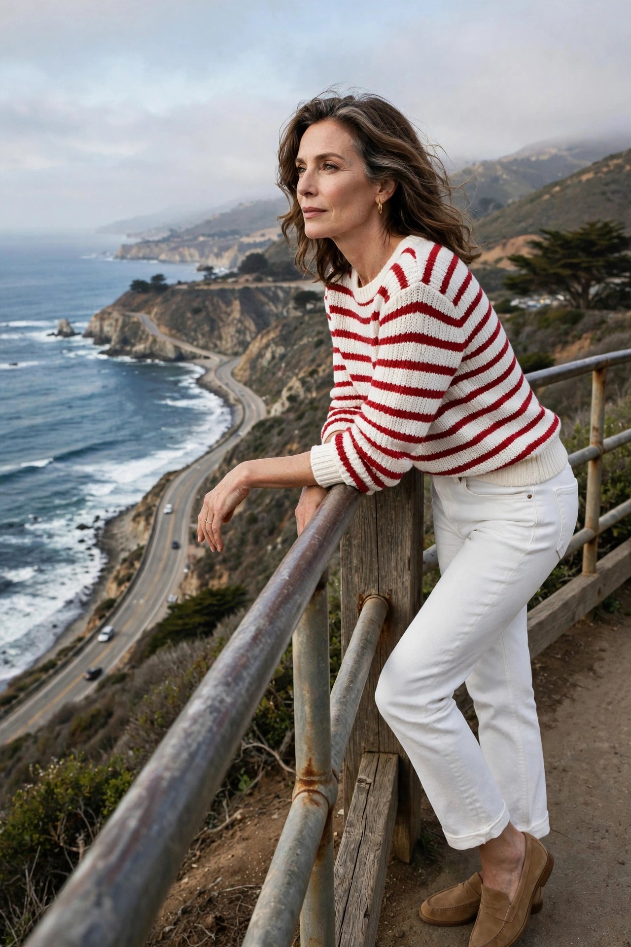 Woman in her 50s in red striped sweater and white jeans at a coastal overlook