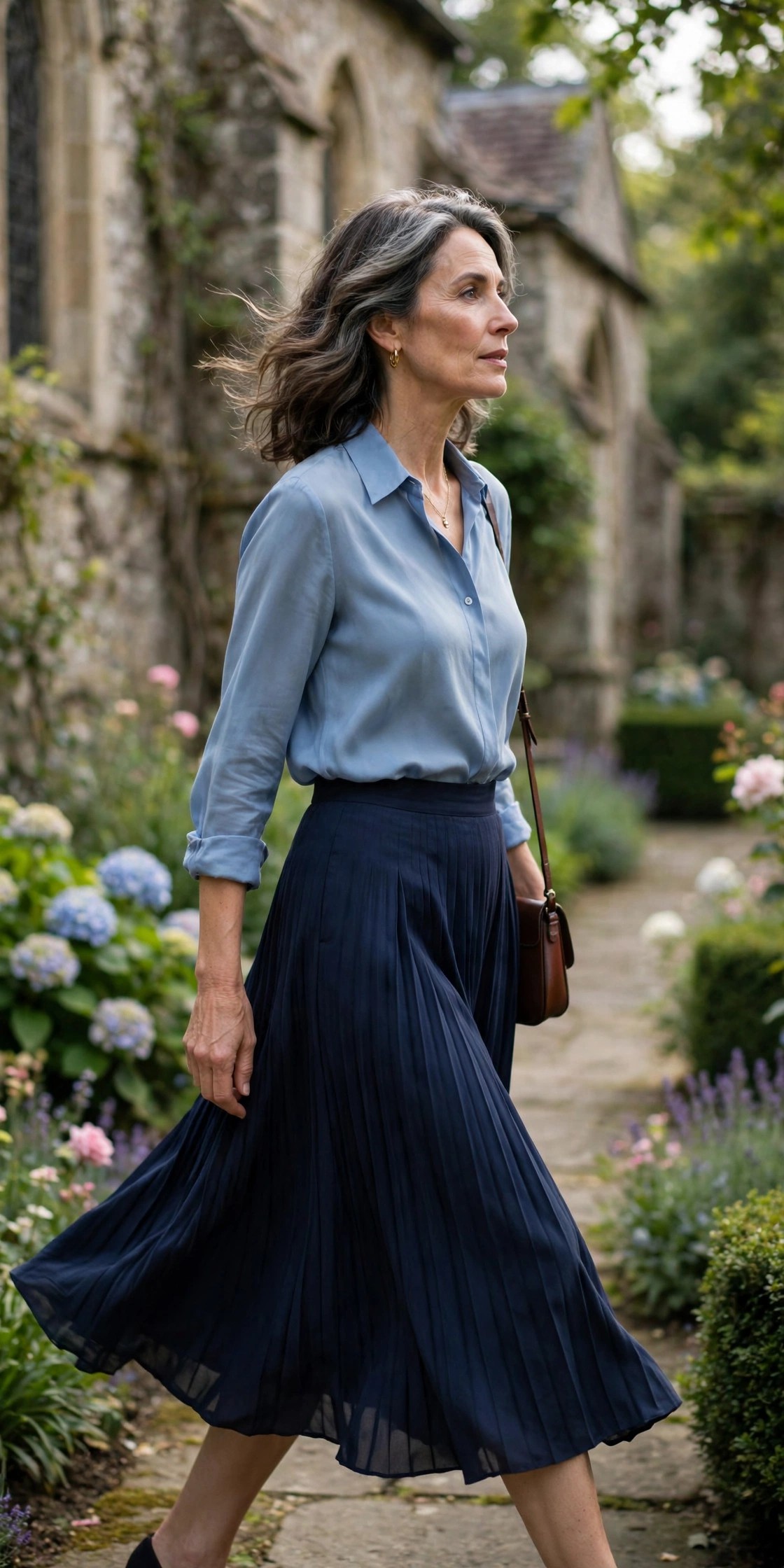 Woman over 50 in a powder blue blouse and navy pleated midi skirt